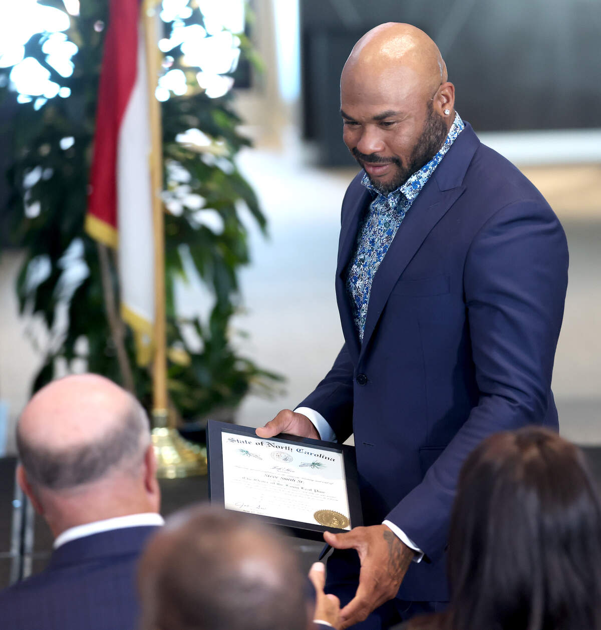 Former Carolina Panthers wide receiver Steve Smith reaches out to shake hands with team owner David Tepper, left, after receiving his certificate to the Order of the Long Leaf Pine at Bank of America Stadium on Wednesday, June 17, 2026. Smith was awarded the honor with other recipients, including Tepper.
