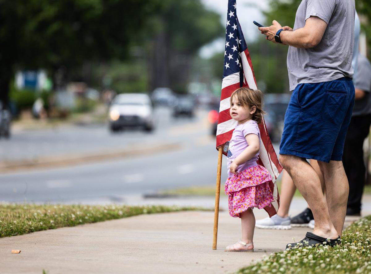 A little girl waits for the funeral procession to the cemetery for CMPD Officer Joshua Eyer in Charlotte, N.C., on Friday, May 3, 2024.
