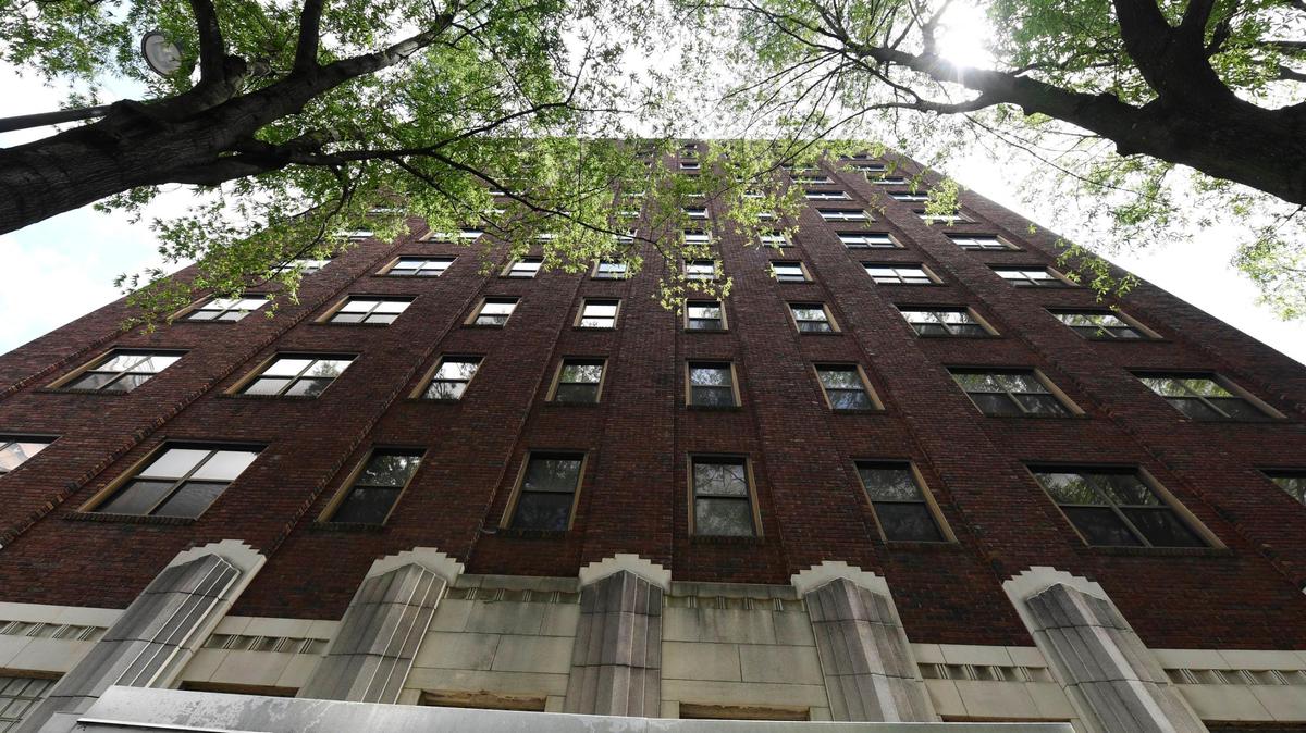 The front of Hall House towers above tree canopy along N. Tryon Street on Thursday, July 30, 2020. The 12-story building, which operated as a hotel before being converted into senior housing, is listed on the National Register of Historic Places.