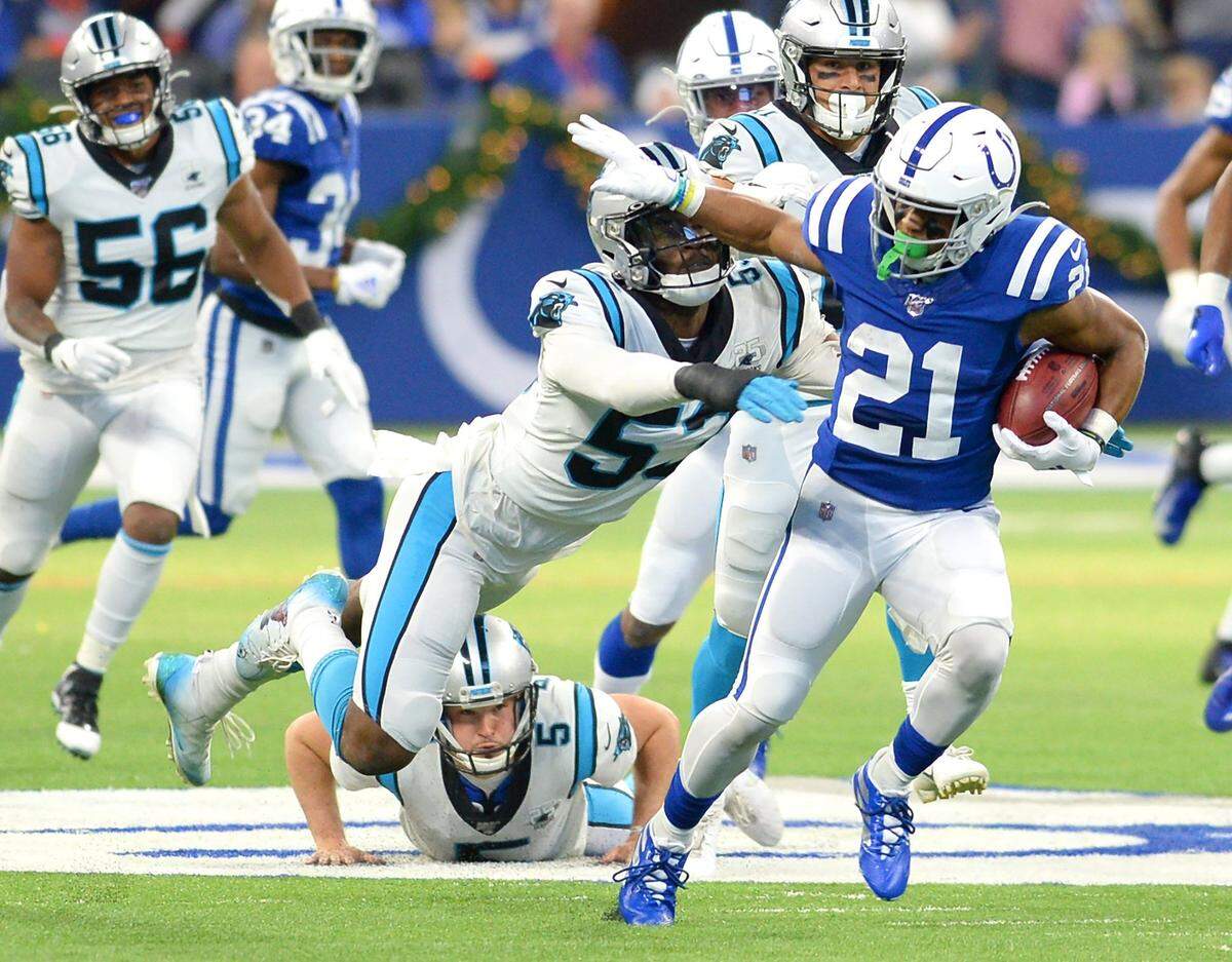 Indianapolis Colts running back Nyheim Hines, right, pushes Carolina Panthers linebacker/defensive end Brian Burns, center, aside on a run during first quarter action at Lucas Oil Stadium in Indianapolis, Indiana on Sunday, December 22, 2019.