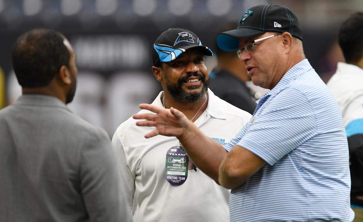Former Panthers player Winslow Oliver, center, talks with current team owner David Tepper, right before a Carolina game in September in Houston.