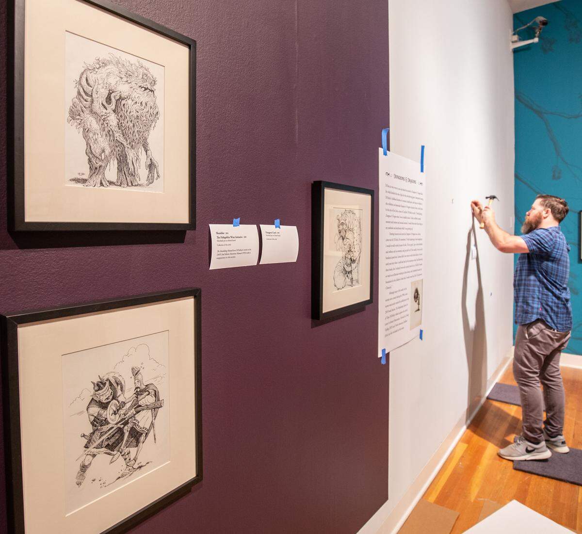 Ian Larson, chief of art services and installation at the Mint Museum, helps install the Tony DiTerlizzi exhibition at the museum’s Randolph Road location. “Never Abandon Imagination: The Fantastical Art of Tony DiTerlizzi” opens June 22.