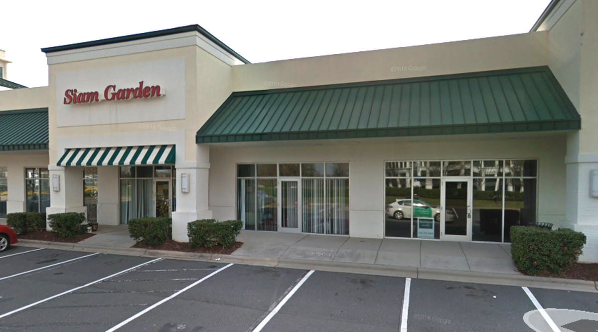 The storefront of Siam Garden, a restaurant in a strip mall. The building is light-colored stucco with a green metal awning and a sign with the restaurant’s name in red letters.