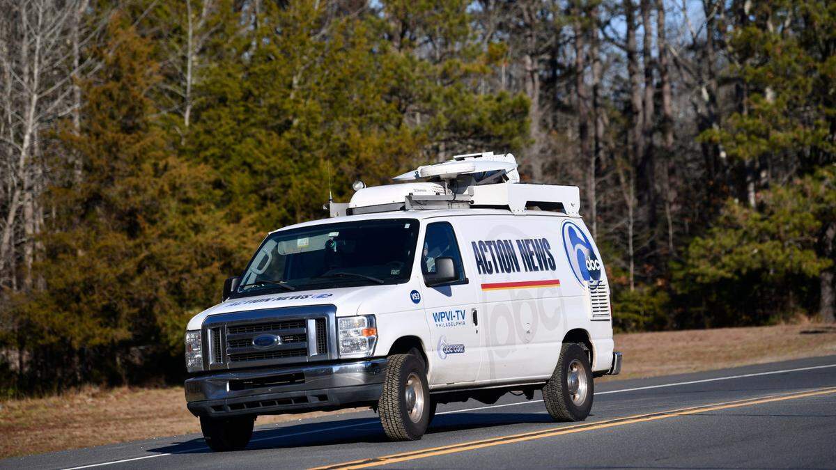 An Action News van exits the parking lot of the Wharton State Forest Atsion office on Wednesday after a pilot and a photographer were killed when their Chopper 6 crashed in a wooded area of Burlington County, New Jersey, on Tuesday night.