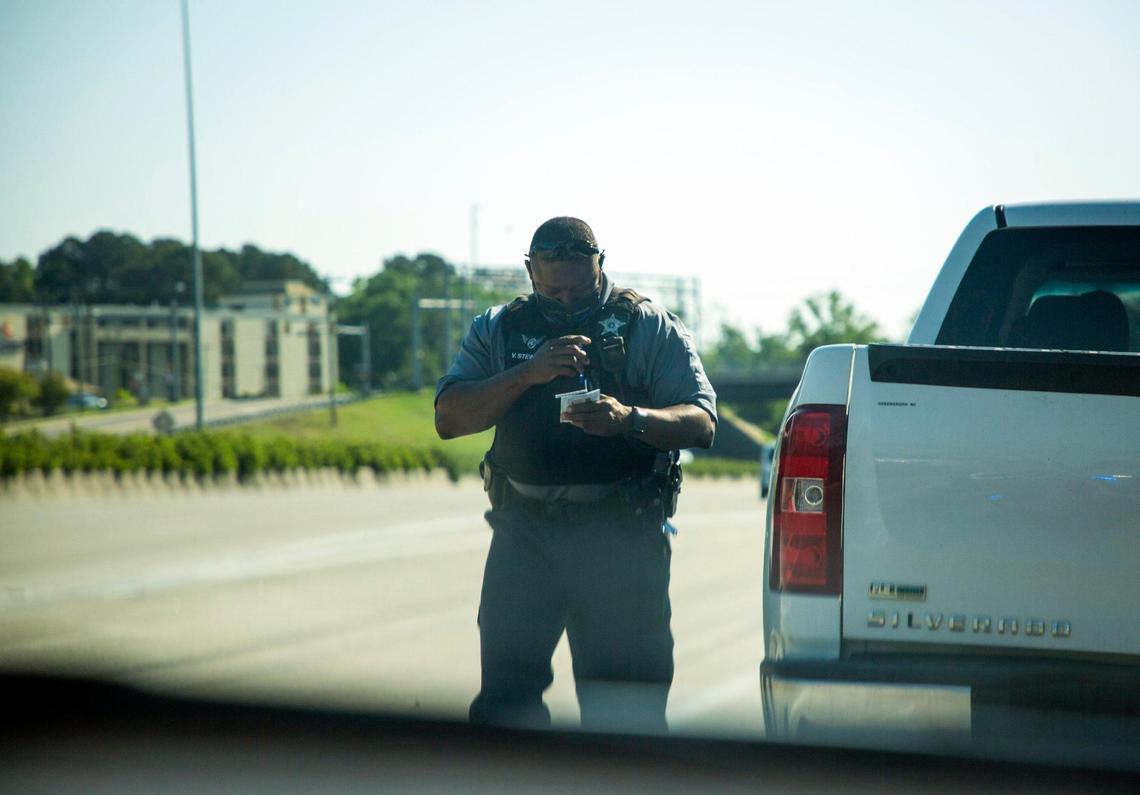 Durham County Sheriff’s Deputy V. Stewart returns to his car with the license and registration of a driver he caught speeding on I-85.