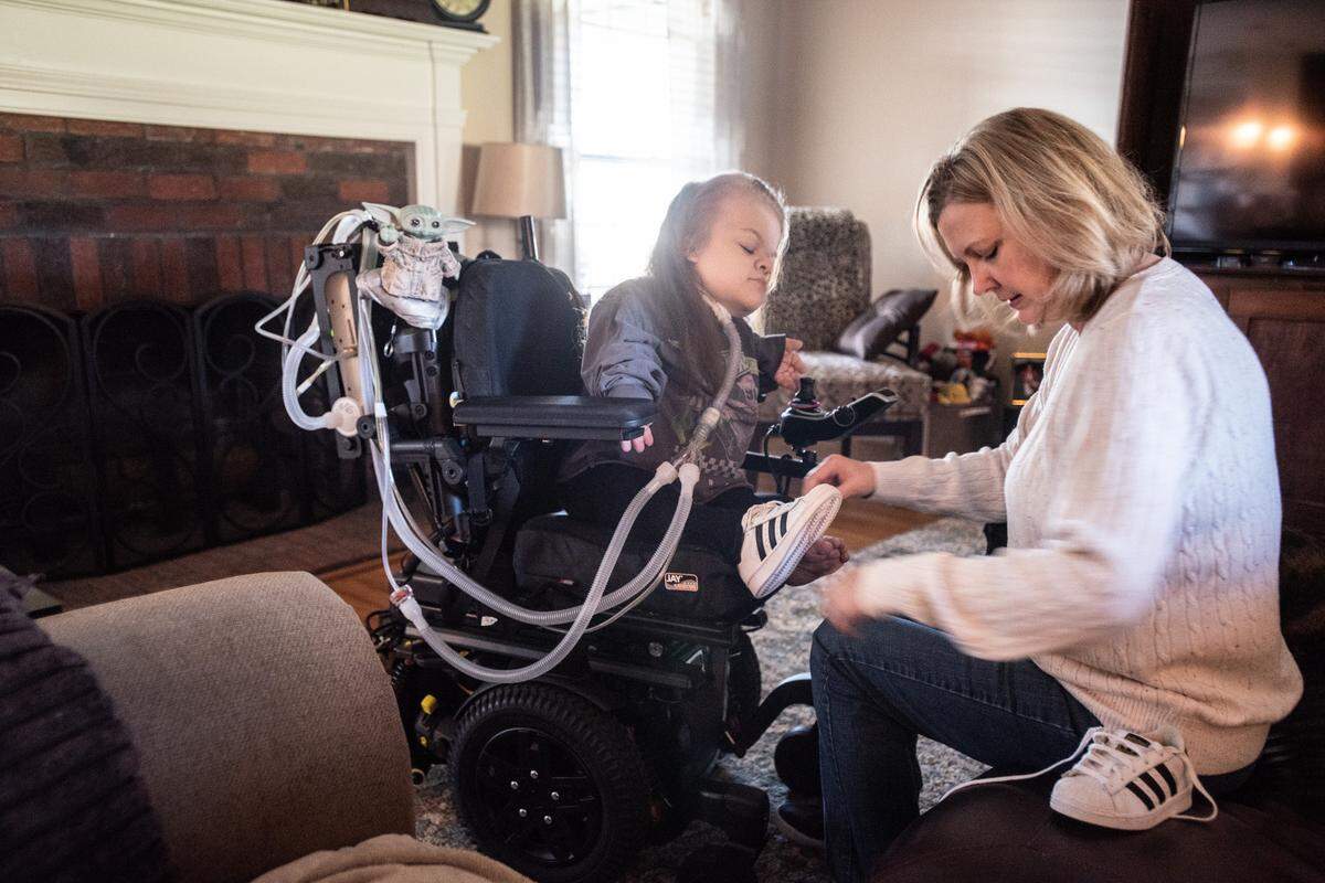 Abby puts her shoes on with the help of her mom, Lisa, at their home in Indian Trail.