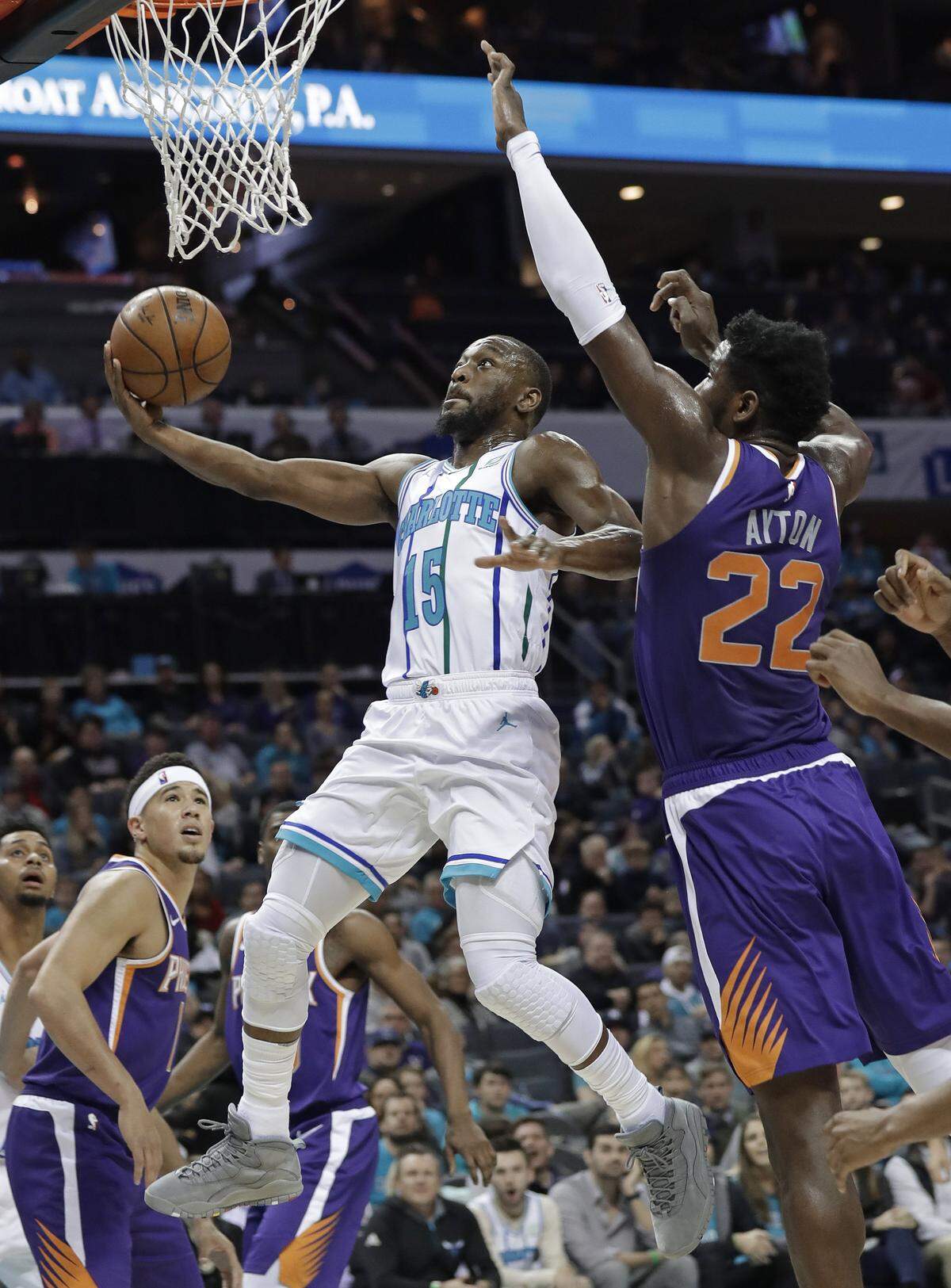Former Charlotte point guard Kemba Walker (15) tries to get a shot up and over the Phoenix Suns’ Deandre Ayton.