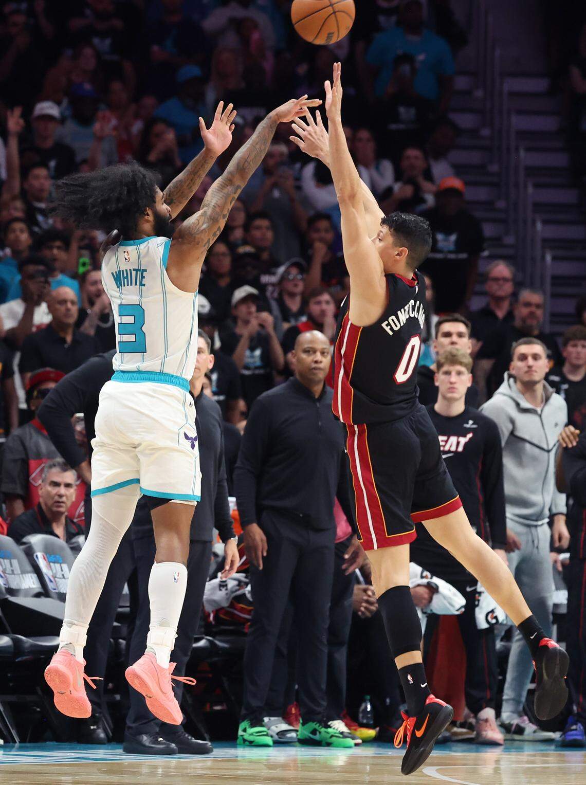 Charlotte Hornets guard Coby White, left, releases a three-point shot over Miami Heat forward Simone Fontecchio, right, during action at Spectrum Center in Charlotte, NC on Tuesday, April 14, 2026. The Hornets defeated the Heat 127-126 in NBA Play-in-Tournament basketball game.