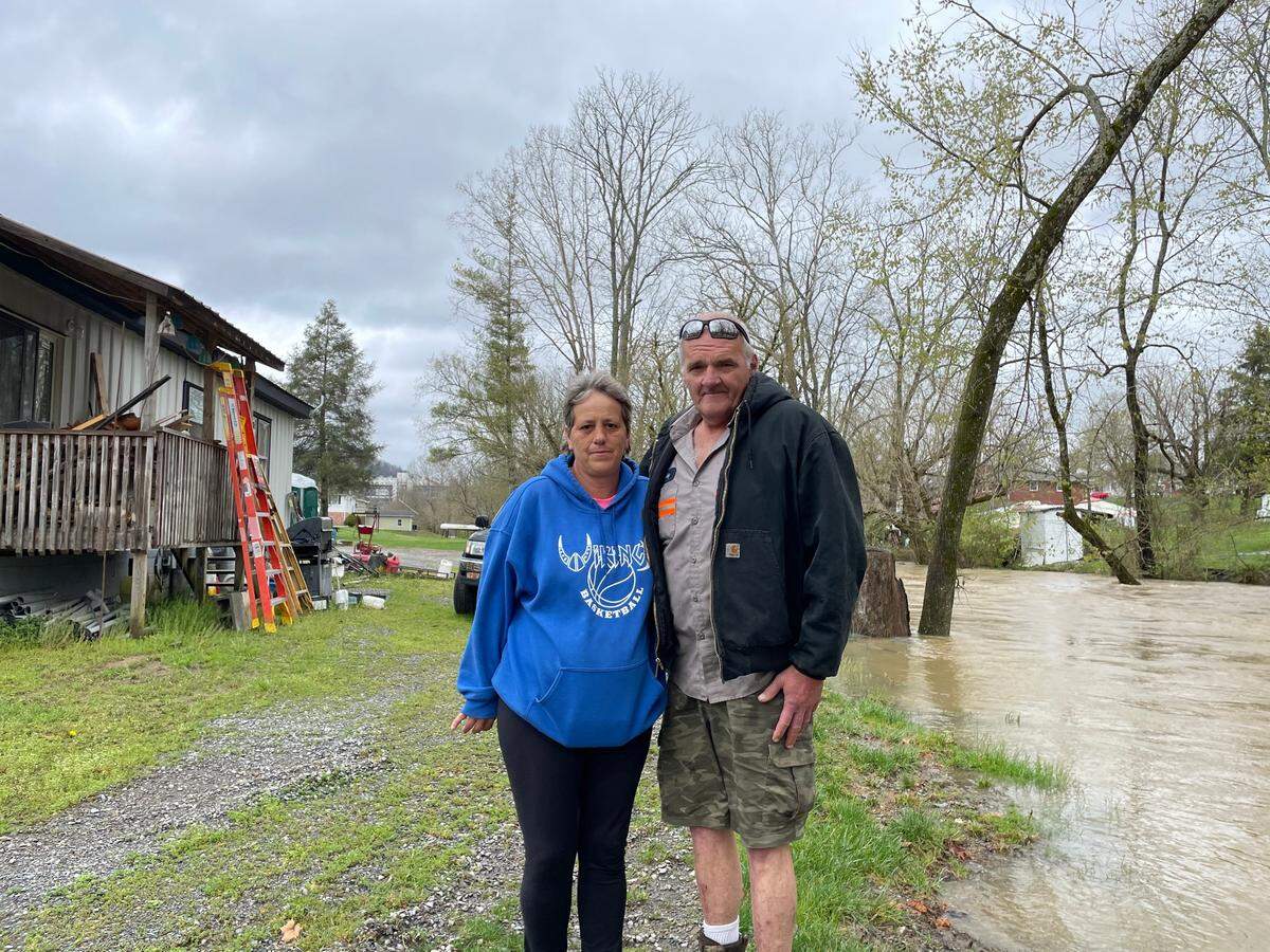 Debbie and Bobby Duncan stand next to the creek that flooded their home in Bristol, Tenn. last year. Rain again caused flash floods in the area this year and forced NASCAR to postpone its dirt race at nearby Bristol Motor Speedway, visible in the background.
