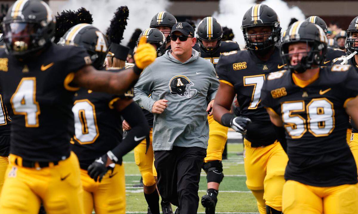 Appalachian State Mountaineers head coach Shawn Clark (middle) runs on the field before a 2022 game against the Troy Trojans at Kidd Brewer Stadium in Boone.