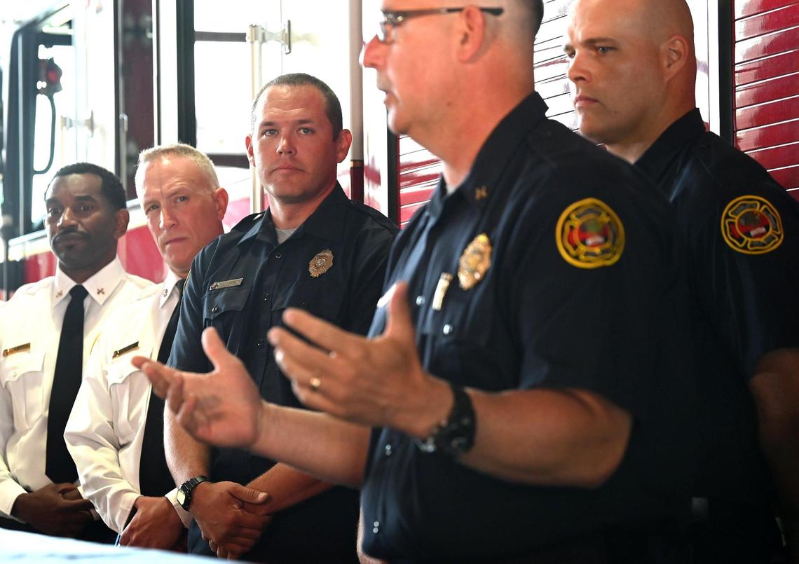 Charlotte firefighter Kevin Murphy, center, listens as Captain Jeff Bright of Station 10 discusses their role in battling the five-alarm fire in SouthPark on May 18.