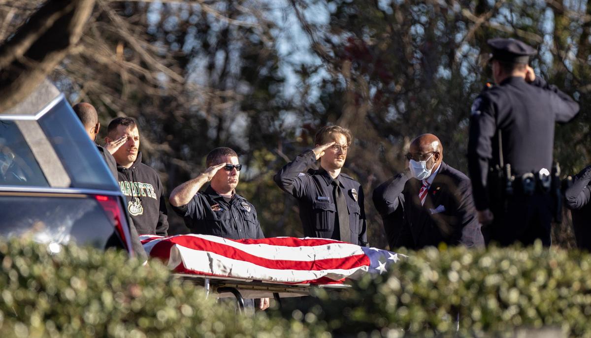Police officers salute as the body of Charlotte-Mecklenburg police Officer Mia Goodwin body is moved out of the hearse outside Alexander Funeral Home Charlotte, N.C., on Thursday, December 23, 2021.