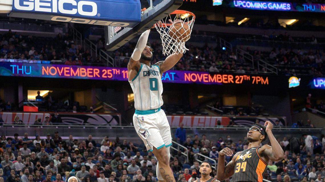 Charlotte Hornets forward Miles Bridges (0) dunks the ball in front of Orlando Magic guard Gary Harris (14) and center Wendell Carter Jr. (34) during the first half of an NBA basketball game, Wednesday, Nov. 24, 2021, in Orlando, Fla. (AP Photo/Phelan M. Ebenhack)