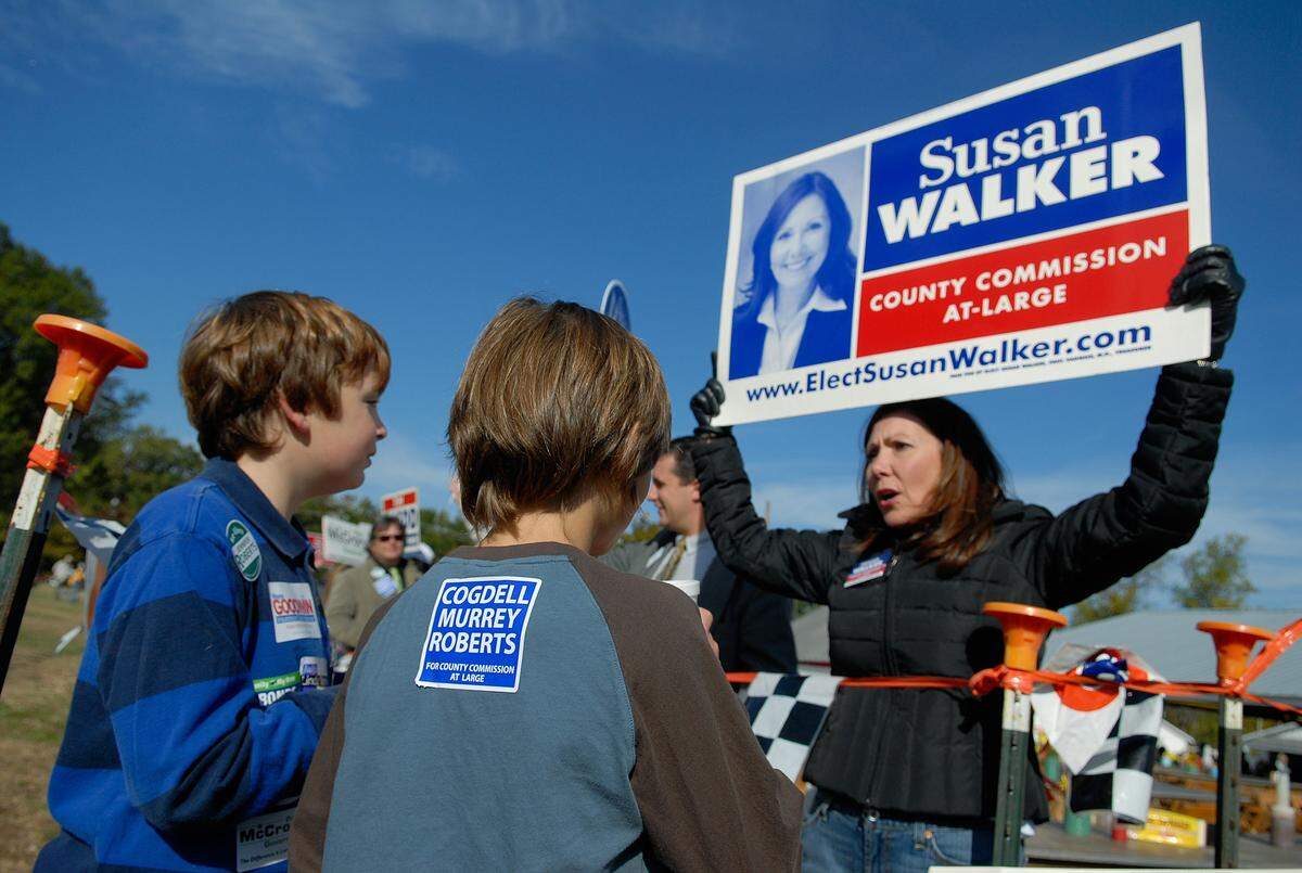 Seth Thompson, 11, and Micah Halter, 11,  chat with Susan Walker, a candidate for Mecklenburg County Commissioner, at the Mallard Creek BBQ onThursday, Oct. 23, 2008 