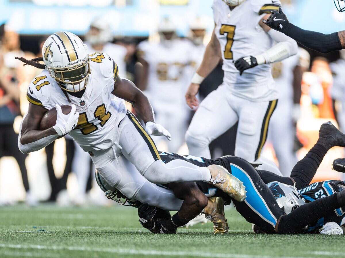 New Orleans Saints running back Alvin Kamara, left, is tackled by Carolina Panthers safety Nick Scott on Sunday at Bank of America Stadium.