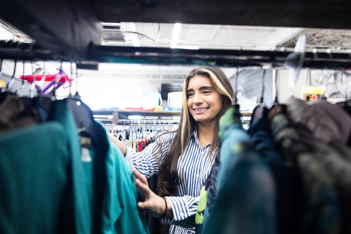Paola Garcia, spokeswoman for Camino, a bilingual and multicultural nonprofit offering holistic care to the underinsured and uninsured, sifts through the clothing racks Aug. 31 at The WearHouse thrift shop in Charlotte.