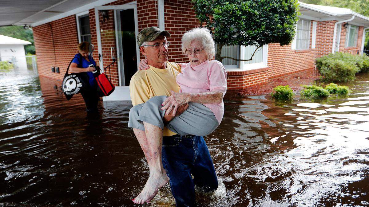 In this Sept. 17, 2018, file photo, Bob Richling carries Iris Darden, 84, out of her flooded home in the aftermath of Hurricane Florence in Spring Lake, N.C.