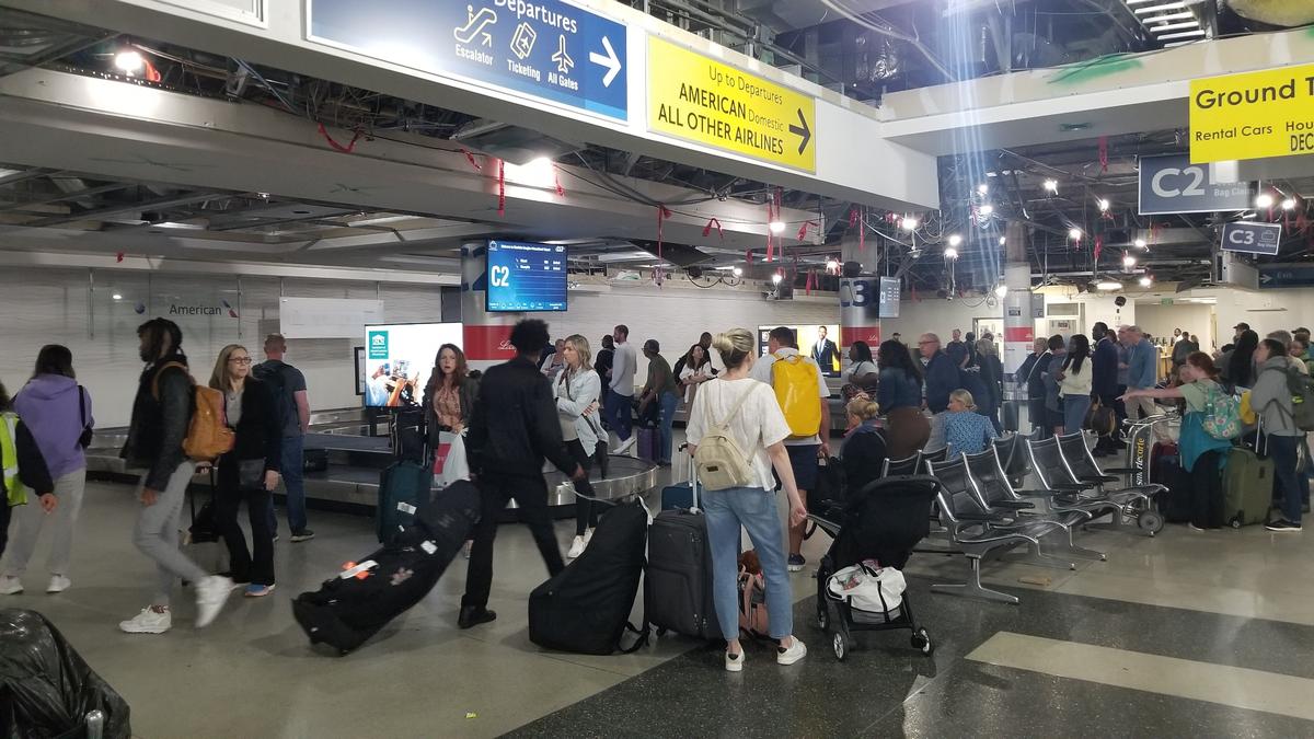Passengers pick up bags at a baggage claim at the Charlotte Douglas International Airport.