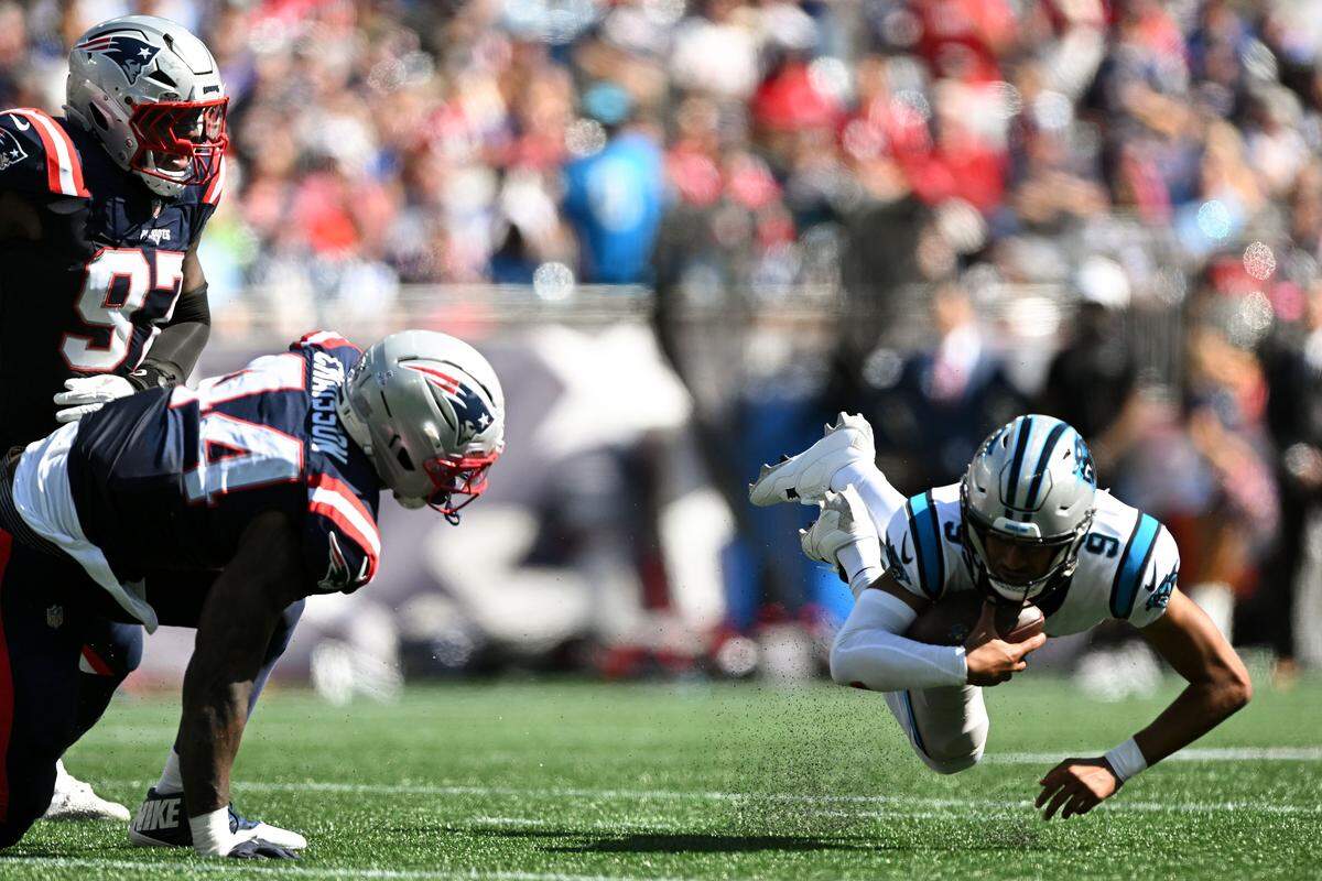 Carolina Panthers quarterback Bryce Young (9) slips and falls under pressure from New England Patriots defensive end Milton Williams (97) and linebacker K'Lavon Chaisson (44) during Sunday’s first half at Gillette Stadium.