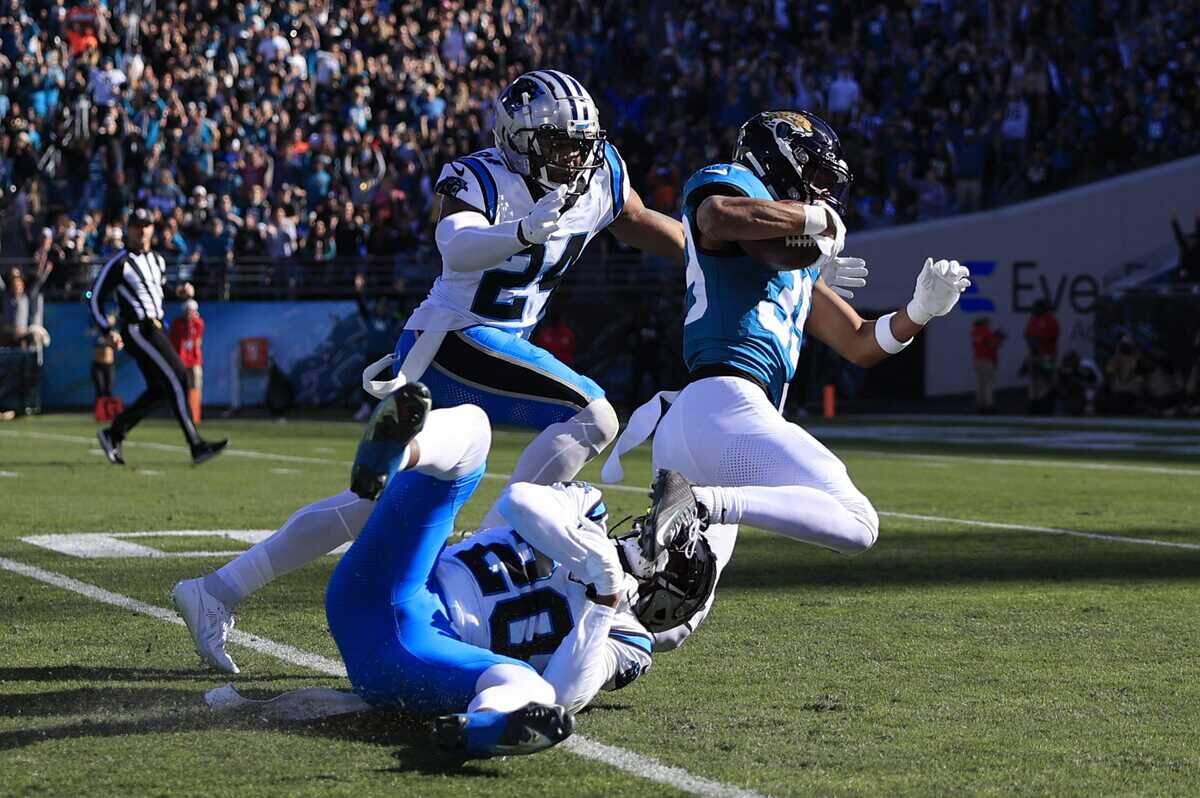 Jacksonville Jaguars wide receiver Jamal Agnew (39) rushes for yards as he is tackled by Carolina Panthers cornerback Shaquill Griffin (20) and safety Vonn Bell (24) during the second quarter of a regular season NFL football matchup Sunday, Dec. 31, 2023 at EverBank Stadium in Jacksonville, Fla.