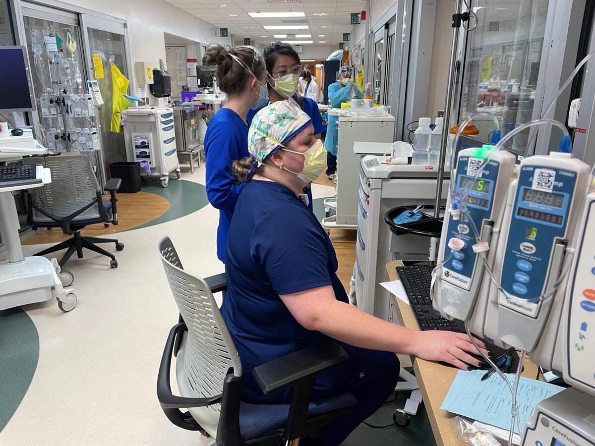 Novant Health ICU team members gather outside a patient’s room to discuss the patient’s progress and treatment options. ICU and other COVID-19 units across North Carolina have been swamped with unvaccinated patients in recent weeks.