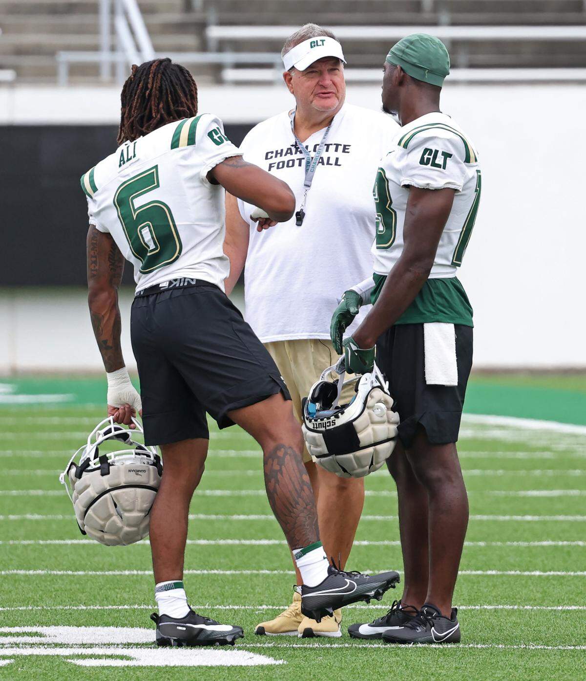 Charlotte 49ers head football coach Biff Poggi, center, speaks with two of his players during the team’s first practice on Friday, August 4, 2023.