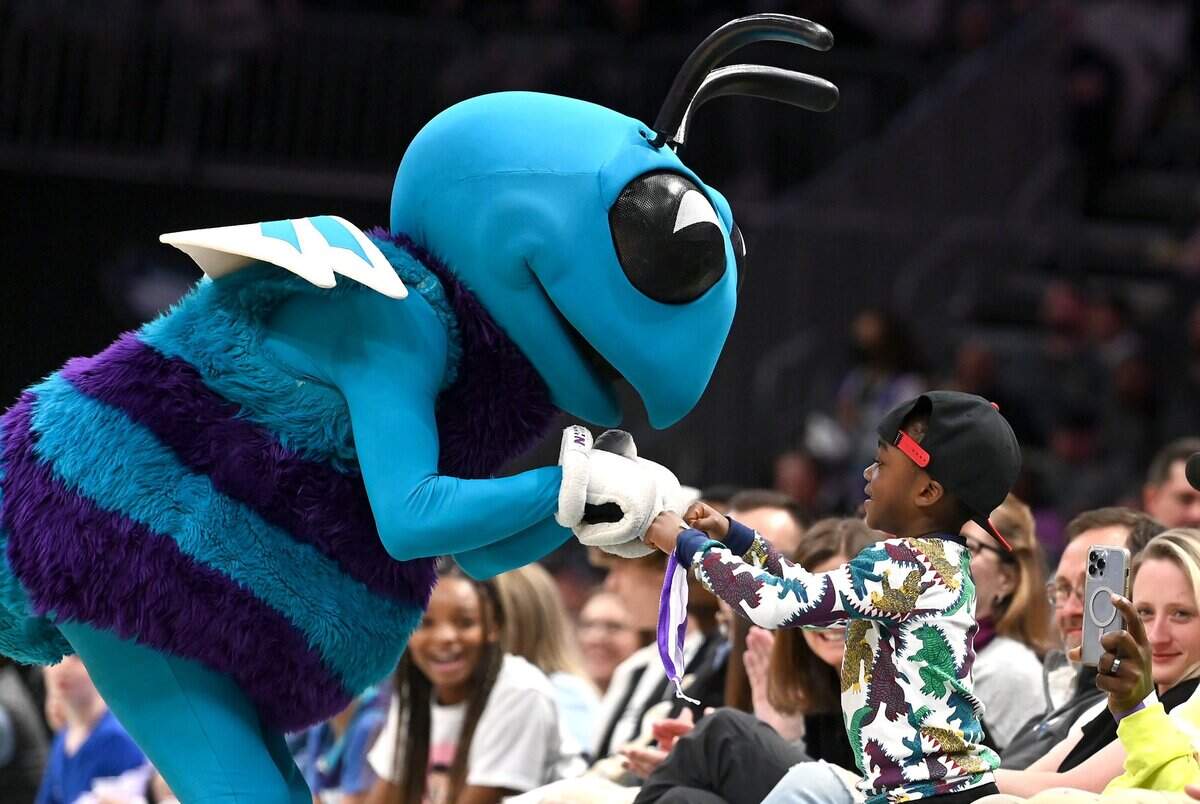 Charlotte Hornets mascot Hugo the Hornet fist bumps a young fan along the court during the teamÕs game against the Washington Wizards at Spectrum Center in Charlotte, NC on Sunday, April 10, 2022. The Hornets defeated the Wizards 124-108.