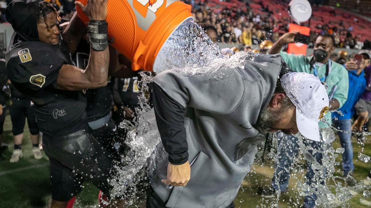 Shelby head coach Mike Wilbanks gets a celebratory bath as the Golden Lions run out the clock to clinch the NCHSAA 2-A championship game with 55-34 victory over Wallace-Rose Hill on Saturday, December 11, 2021 at Carter-Finley Stadium in Raleigh, N.C.
