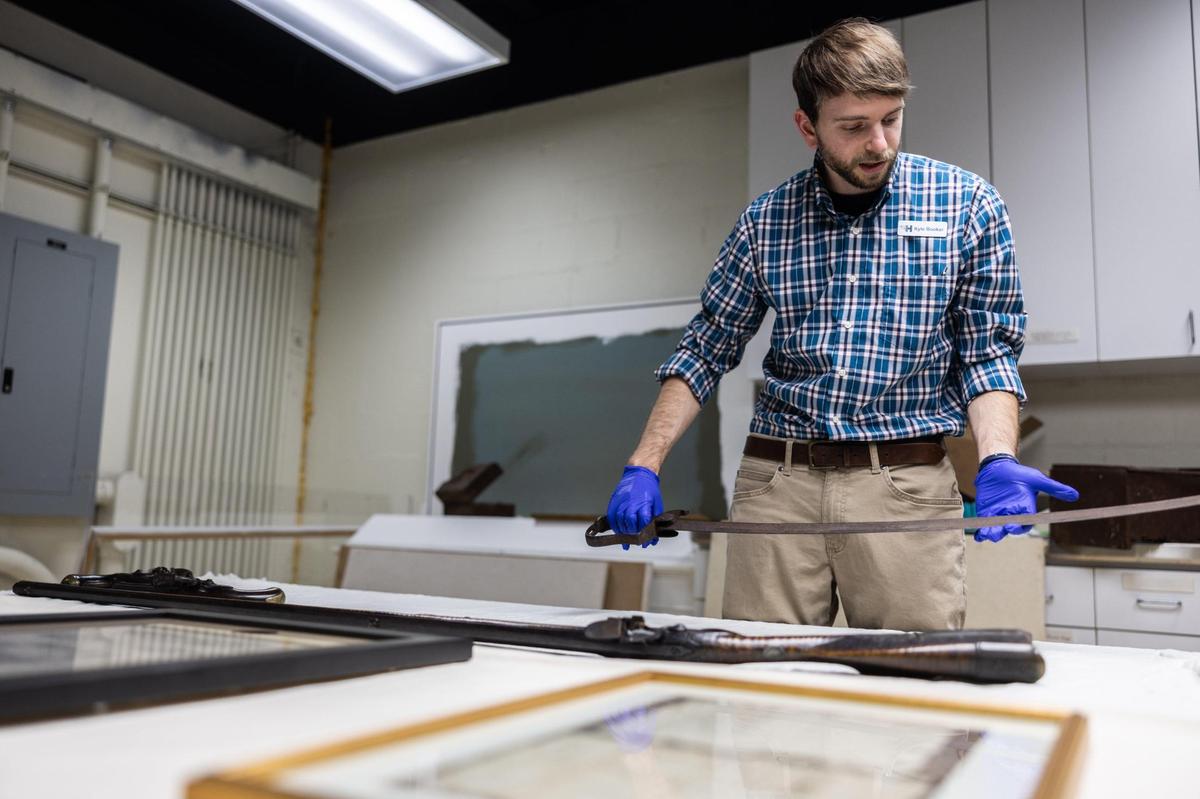 Charlotte Museum of History Collections Manager Kyle Booker shows historical items related to the Mecklenburg Declaration of Independence. The museum is launching a new exhibit for the 250th anniversary of the Meck Dec. Booker is handling a sword made in the forge of one of the document’s signers. Nearby sits firearms owned by John McKnitt Alexander, the secretary of the May 20 convention. 