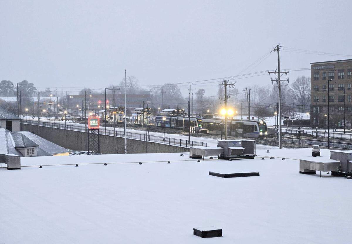 A thin cover of wintry mix covers McCullough Station of as a Blue Line train runs along the tracks in Charlotte on Sunday, on January 25, 2026.