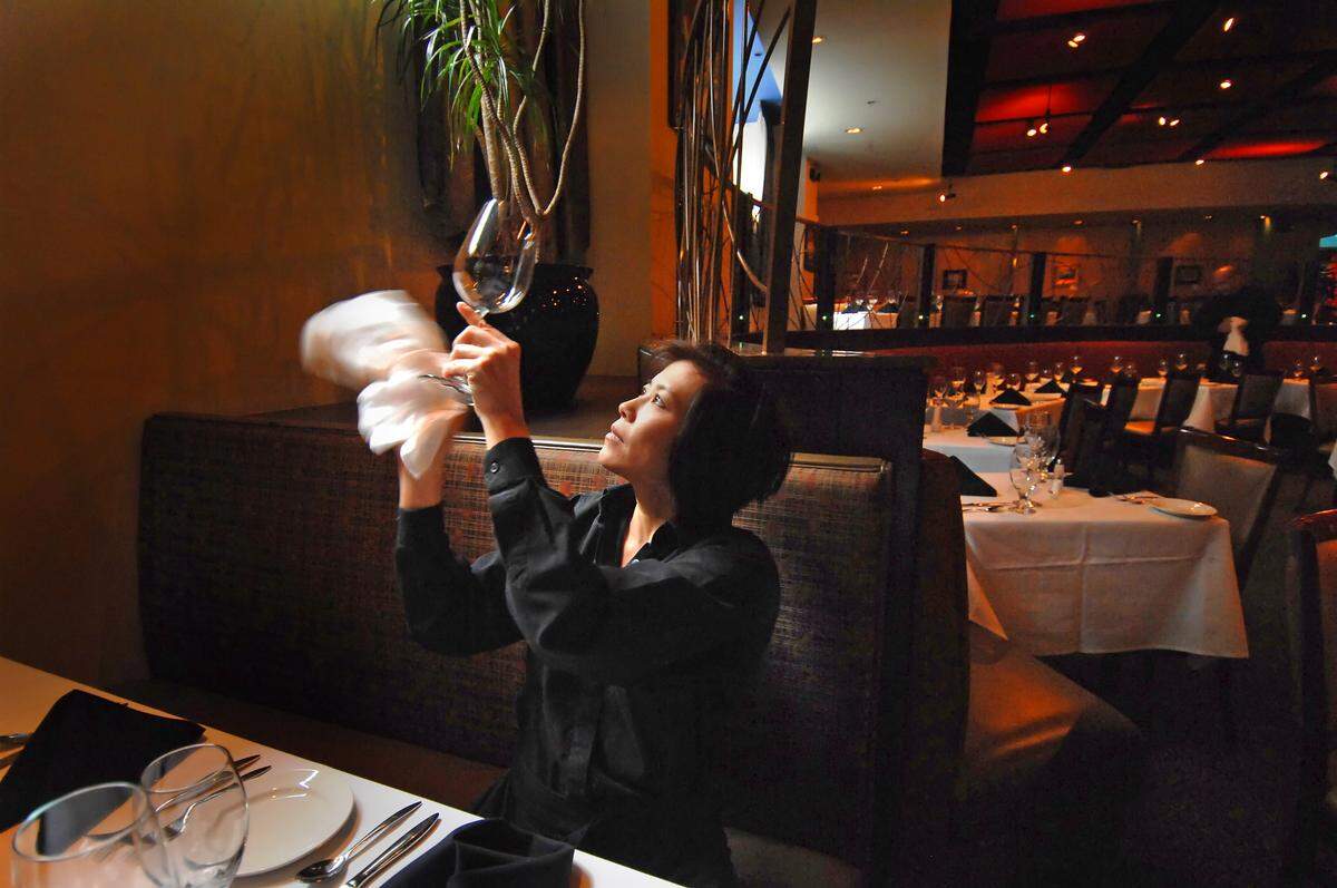 Server Diane Yee holds a goblet up to the light as she polishes glassware prior to opening for dinner at Blue in uptown Charlotte in March 2008.
