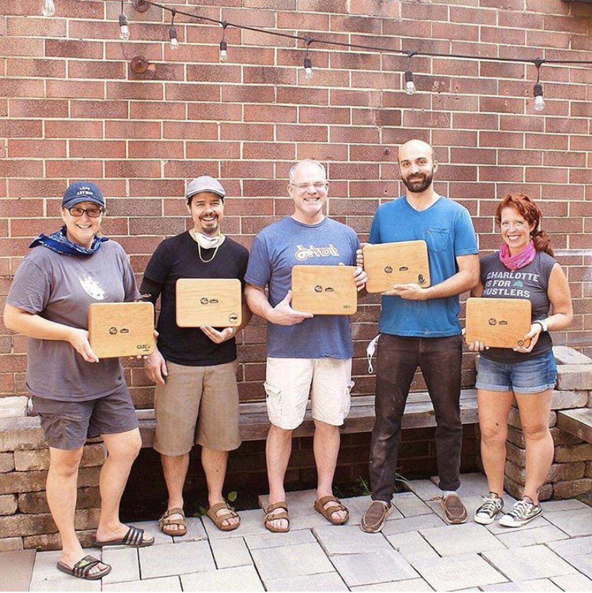 From left, woodworkers Kristen Gurri, Adam Jochim, Mark Doepker, Ian Wegener and Emily Berger display their charcuterie boards created for Verse & Vino in partnership with ArtPop, Lowe’s and the Charlotte Mecklenburg Library Foundation.