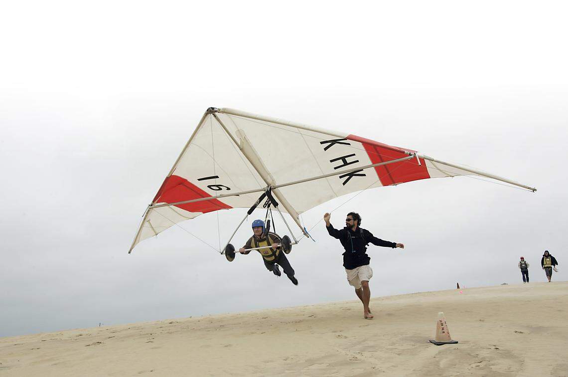 Simon Wright of New York takes flight on the dunes at Jockey’s Ridge State Park, with guidance from ihis instructor from Kitty Hawk Kites’ flight school. The school, founded in 1974, is one of the largest hang gliding school in the world.