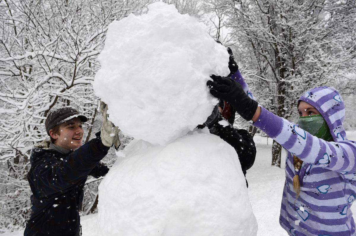 David Butt, 13, and Rachel Bolme, 13, steady the head of a six-foot plus tall snow person on Netherhall Drive in northeast Charlotte on in February 2014.