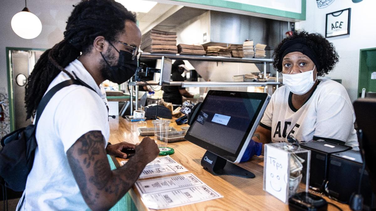 Terrence Richard, left, places an order Thursday with Ace No. 3 employee Ebony Miller. Many people who responded to a Charlotte Observer survey this week said they continue to wear a mask even though they’re vaccinated against COVID-19.