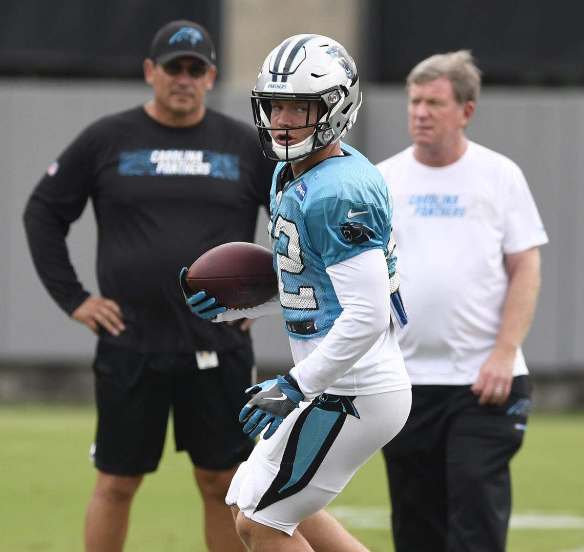 Carolina Panthers running back Christian McCaffrey (22) makes a reception in front of head coach Ron Rivera (left) and general manager Marty Hurney. McCaffrey, entering his third NFL season, was drafted in the first round by Hurney in 2017.