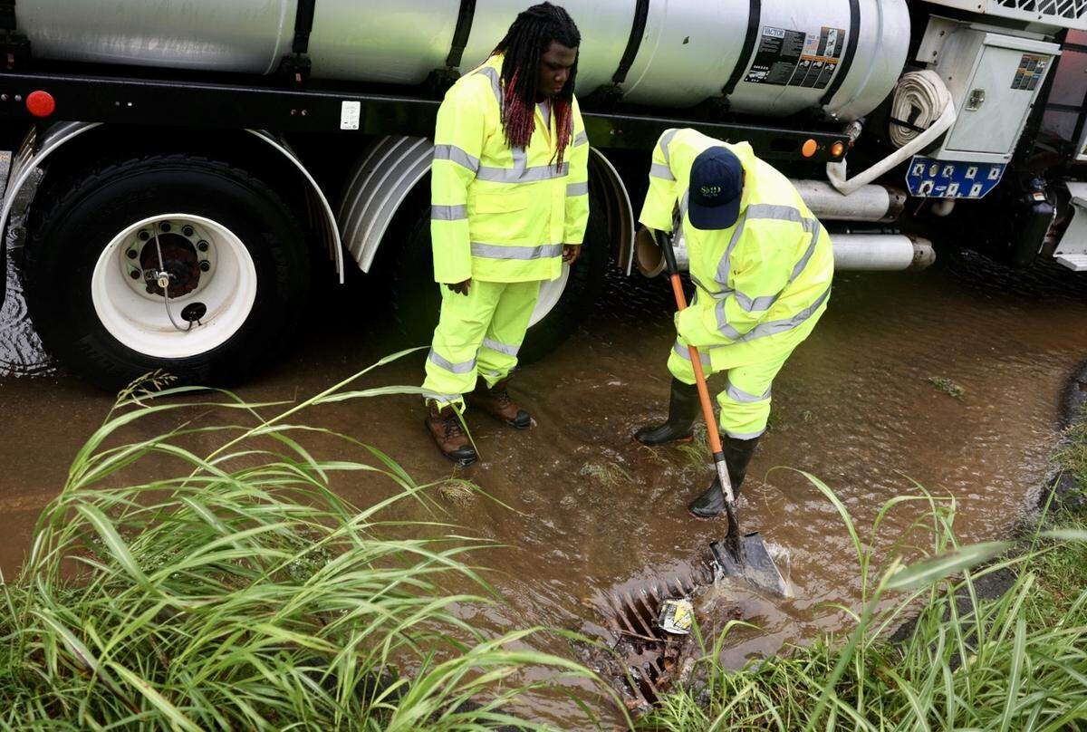 Angela England and Travis Howard with the street maintenance division of the city of Charlotte work to unclog a drain on Parkway Avenue on Thursday, August 8, 2024.