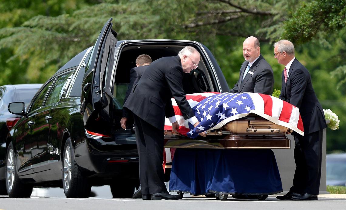 The flag-draped casket of Bruton Smith is removed from a hearse at Central Church in Charlotte, NC on Thursday.