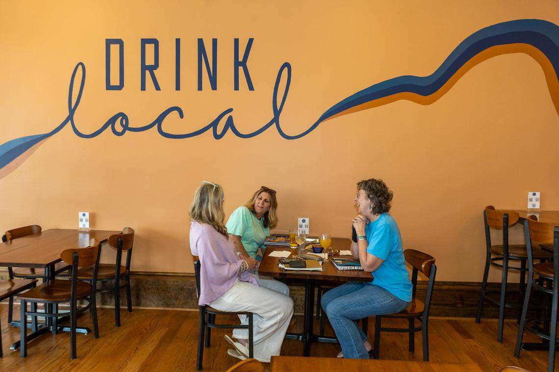 Kathleen Reeder, owner of The Bead Lady; Ashley Howell, owner of The Lenz Studio; and Cindy Sheppard, owner of ShoeBeeDo, congregate at Local Bottle Shop in downtown Concord.