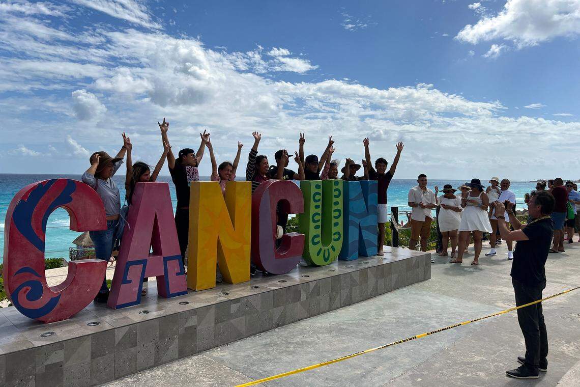 Tourists pose for a photo in front of a Cancun sign in Playa Delfines (Dolphin Beach), Quintana Roo state, Mexico, on November 8, 2022. (Photo by Daniel SLIM / AFP) (Photo by DANIEL SLIM/AFP via Getty Images)