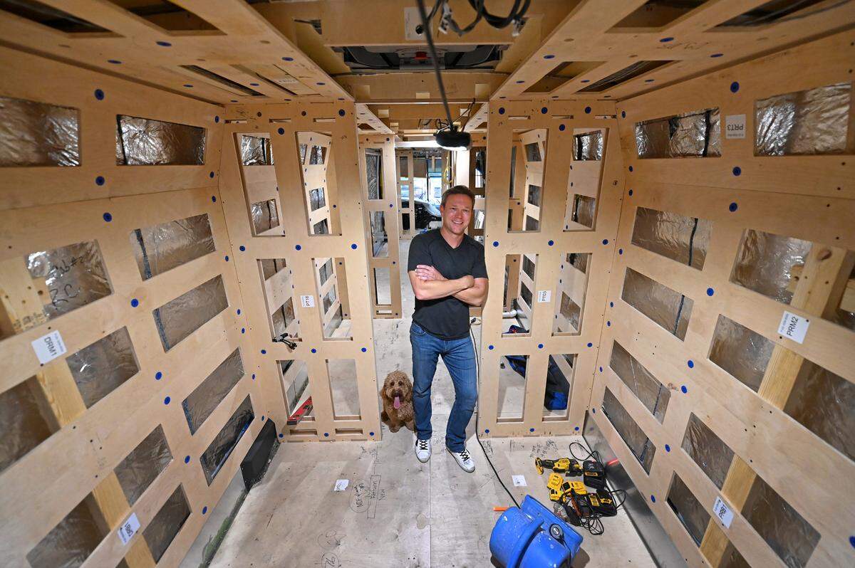 Justin Ward, CEO of Encore Luxury Coaches and Auggie, a mini goldendoodle, inside one of the company’s crew buses at their Cornelius factory.