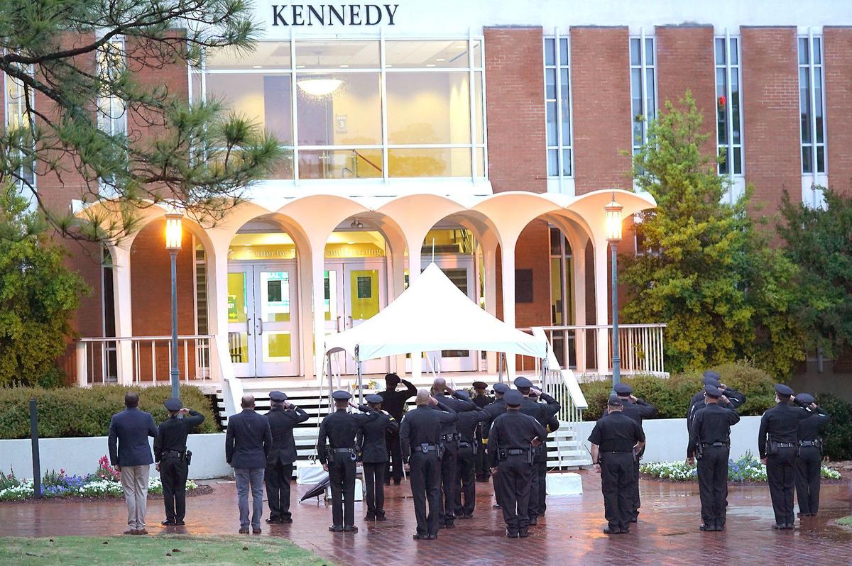 UNC Charlotte police officers and school officials stand at attention after two wreaths were placed at the foot steps of the Kennedy Building.