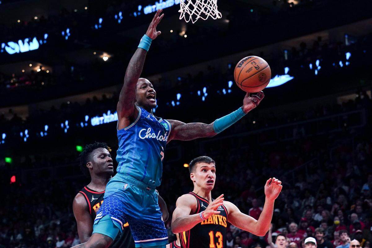 Charlotte Hornets guard Terry Rozier (3) reaches for a rebound next to Atlanta Hawks guard Bogdan Bogdanovic (13) during the second half of an NBA play-in basketball game Wednesday, April 13, 2022, in Atlanta. (AP Photo/John Bazemore)