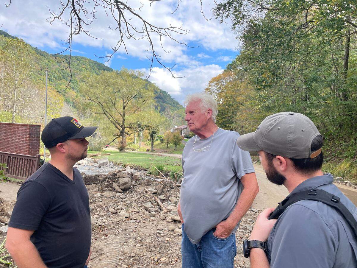 Phillip Hughes, 74, stands between brothers Tyler Lee (left) and Addison Lee (right), telling stories of Helene’s wrath and his childhood along roaring creek.