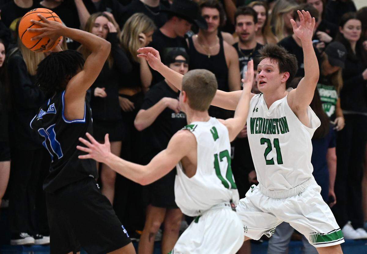 Weddington High defenders AJ Cook, left and Kyle Frazier, right, apply defensive pressure on MooresvilleÕs Aishus Stewart, left, during the second round of NCHSAA action on Thursday, February 24, 2022. Weddington is top a top 25 nationally ranked team.