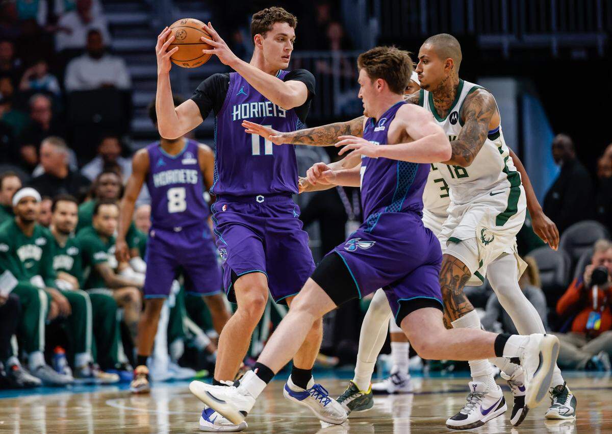 Hornets center Ryan Kalkbrenner, left, keeps the ball away from Bucks forward Kyle Kuzma as Hornets teammate Kon Knueppel rushes to help during the game at Spectrum Center in Charlotte, NC on Wednesday, November 12, 2025.