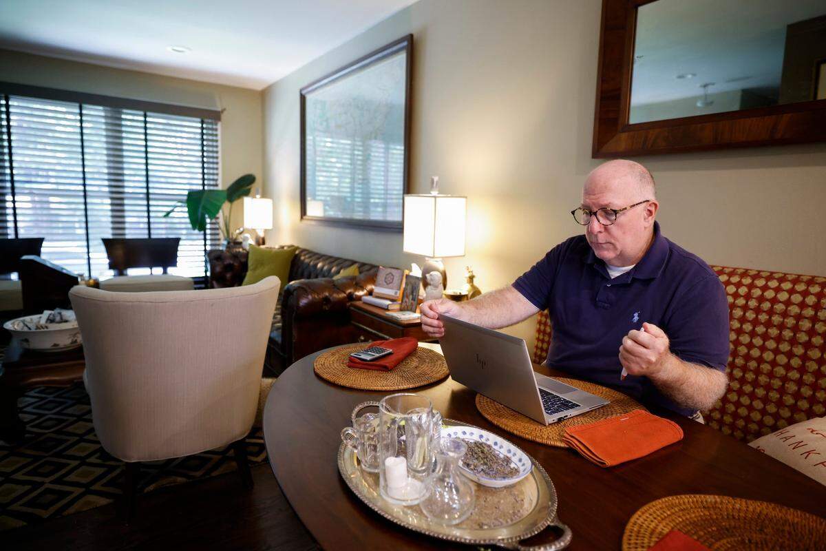 Dan Johnson works at his laptop in his home in the Plaza Shamrock neighborhood. He moved in 2021 to his new location and says he misses the location of his old home in the Elizabeth neighborhood, but is generally happier in his new one.