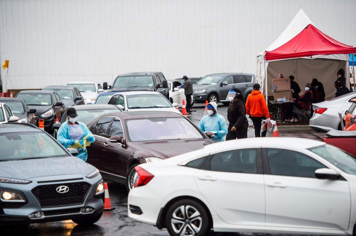 Healthcare workers tend to cars waiting in line for COVID tests at StarMed Healthcare on Tuckaseegee Road on Thursday, December 30, 2021 in Charlotte, NC.