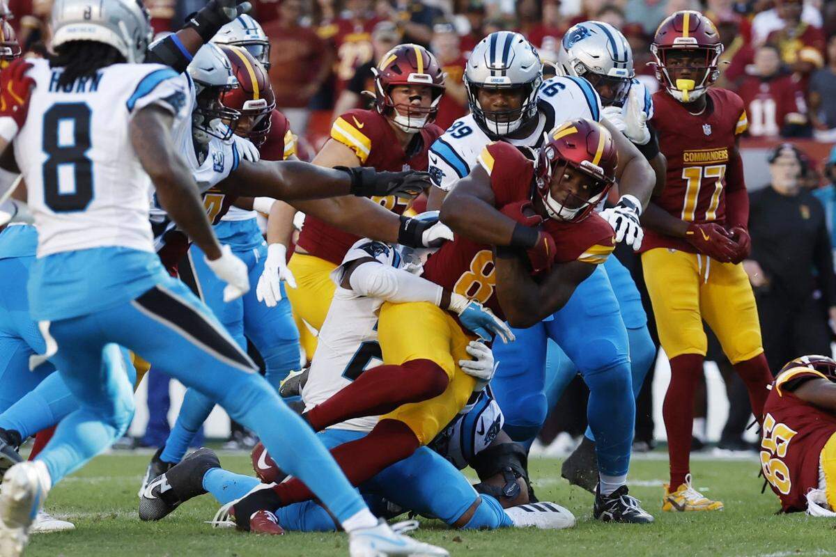Oct 20, 2024; Landover, Maryland, USA; Washington Commanders running back Brian Robinson Jr. (8) is tackled by Carolina Panthers safety Nick Scott (21) during the first quarter at Northwest Stadium. Mandatory Credit: Geoff Burke-Imagn Images
