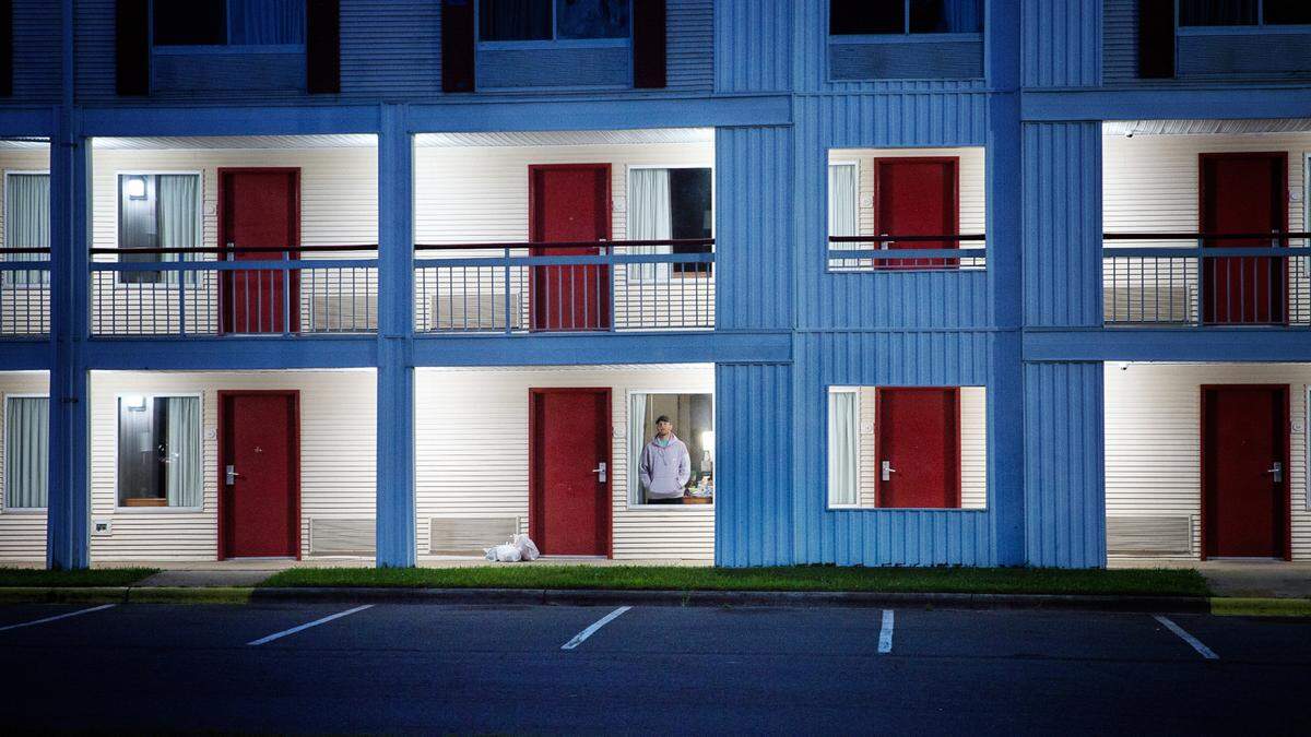 Aaron Hall, 32-year-old from Kansas City, seen through a window of the Econo Lodge near the Charlotte Douglas International Airport, where he stayed 10 days and nine nights in August after testing positive for COVID-19. Hall traveled to Charlotte from Chicago looking for a used Volvo 240 before getting sick from the coronavirus.